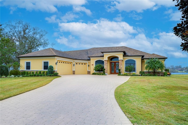 mediterranean / spanish-style home featuring a garage, a front yard, and french doors