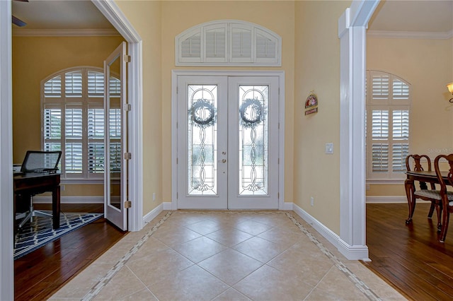 tiled entrance foyer featuring crown molding and french doors