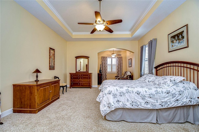 bedroom featuring ceiling fan, ornamental molding, a tray ceiling, and light carpet