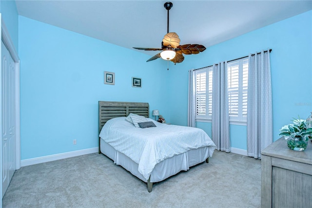 bedroom with light colored carpet, ceiling fan, and a closet