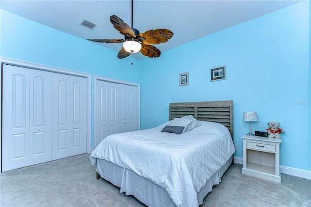 carpeted bedroom featuring two closets and ceiling fan