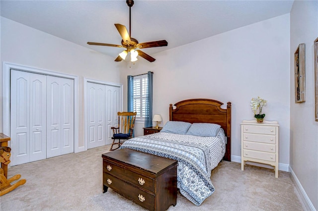 carpeted bedroom with ceiling fan and two closets