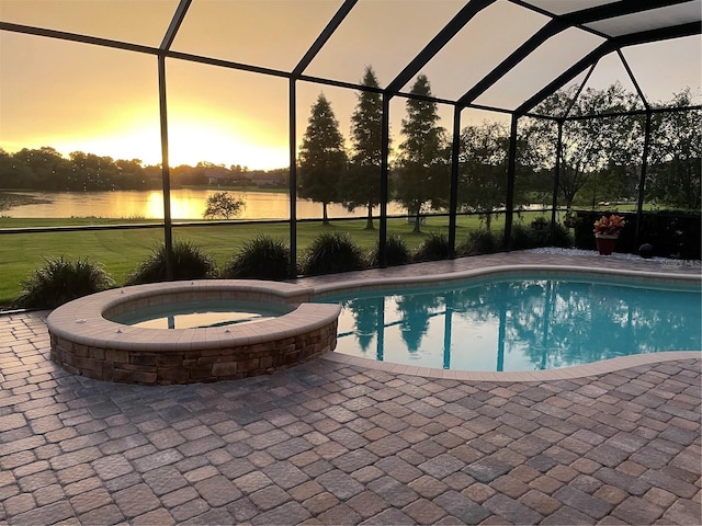 pool at dusk with a water view, an in ground hot tub, a patio area, and glass enclosure