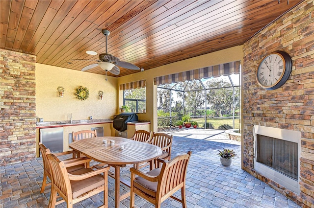 exterior space with area for grilling, ceiling fan, sink, and an outdoor stone fireplace