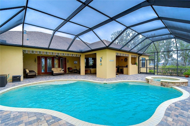 view of pool with an in ground hot tub, a patio area, and glass enclosure