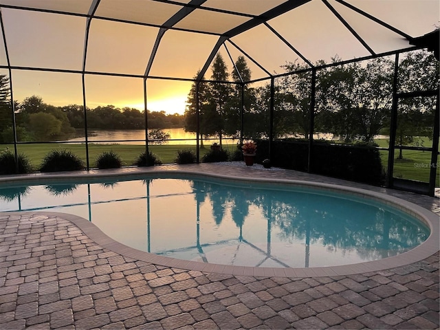 pool at dusk featuring a patio and glass enclosure