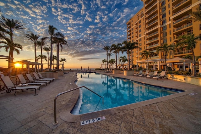 pool at dusk featuring a patio area