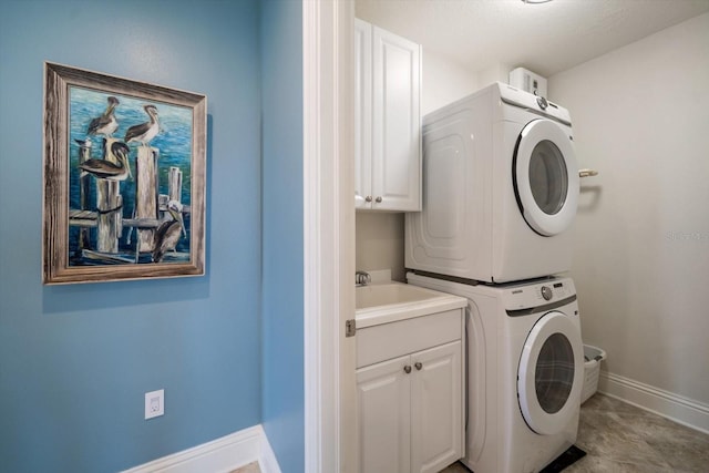 laundry room featuring stacked washer / dryer, sink, and cabinets