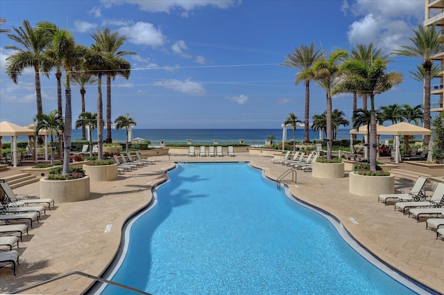 view of pool with a water view and a patio