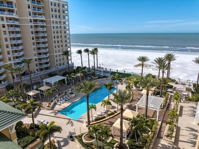 view of pool featuring a water view, a patio, and a beach view