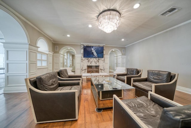 living room featuring a fireplace, ornamental molding, a chandelier, and hardwood / wood-style floors