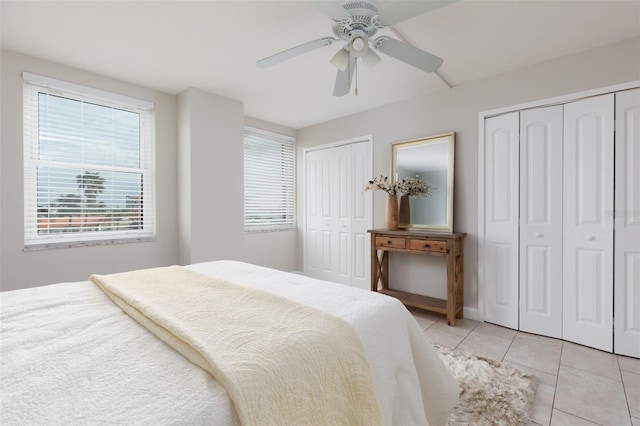 bedroom with ceiling fan, two closets, multiple windows, and light tile patterned floors