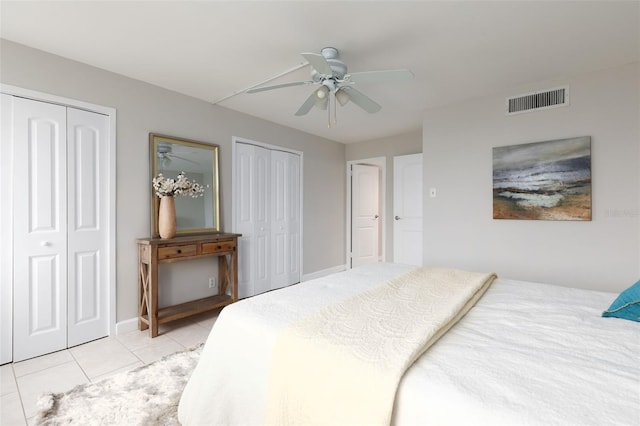 bedroom with ceiling fan, light tile patterned flooring, and two closets