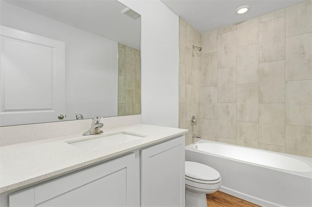 full bathroom with hardwood / wood-style flooring, toilet, vanity, and tiled shower / bath combo