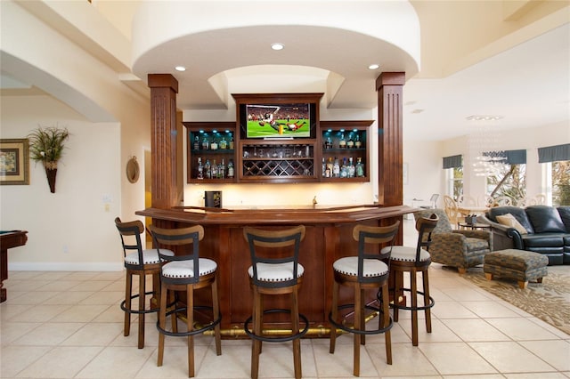 bar featuring light tile patterned floors and decorative columns