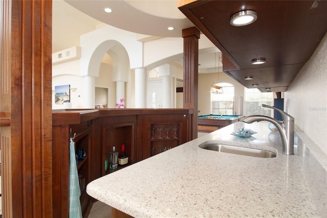 kitchen featuring light stone countertops, pool table, hanging light fixtures, and sink