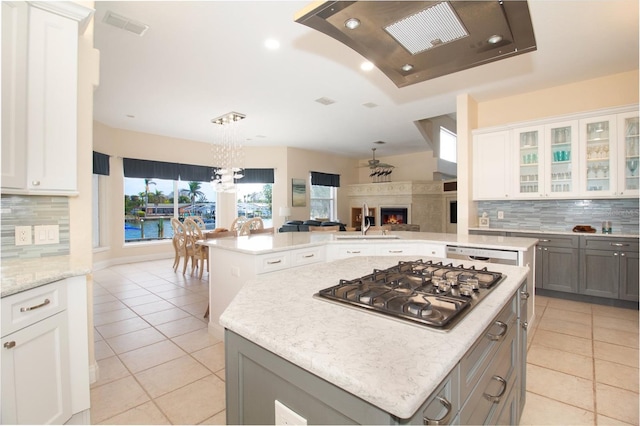 kitchen with white cabinets, a center island, gray cabinetry, light tile patterned flooring, and stainless steel gas stovetop