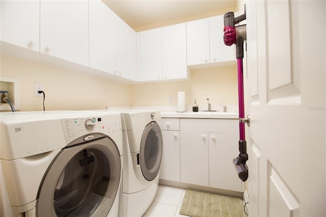 laundry area featuring light tile patterned floors, sink, washing machine and clothes dryer, and cabinets