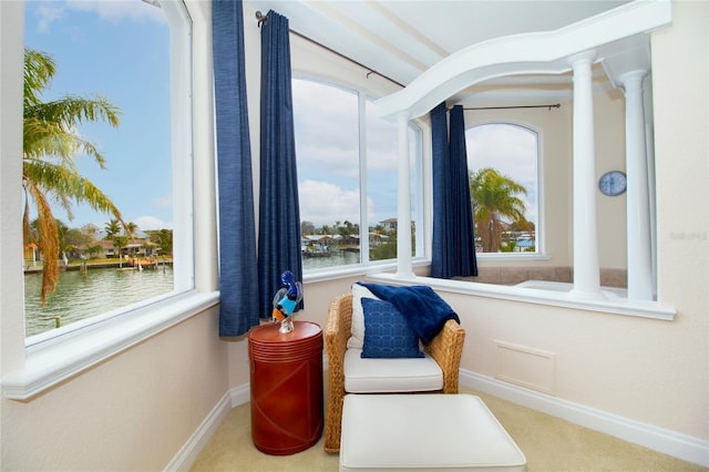 living area featuring a water view and ornate columns