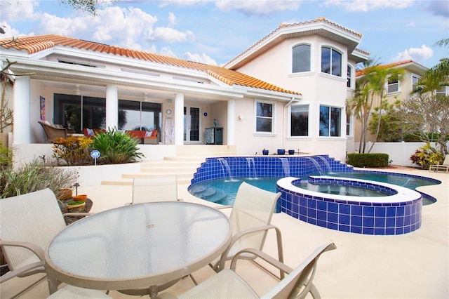 rear view of property featuring a patio area, a swimming pool with hot tub, and pool water feature