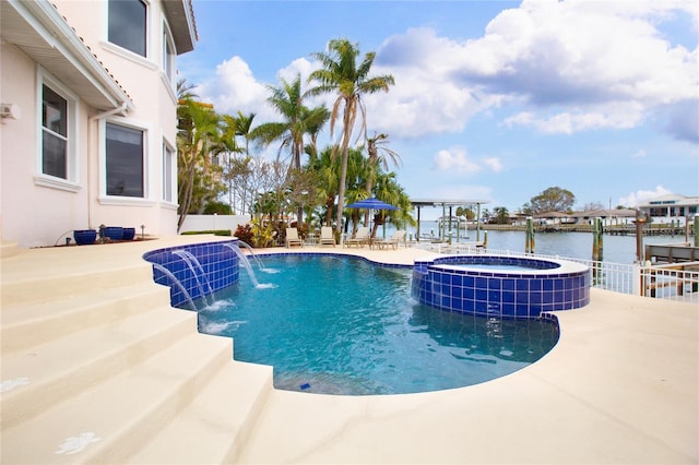 view of swimming pool featuring pool water feature, a water view, an in ground hot tub, and a patio