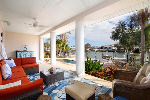 view of patio with ceiling fan, a dock, an outdoor living space, and a water view