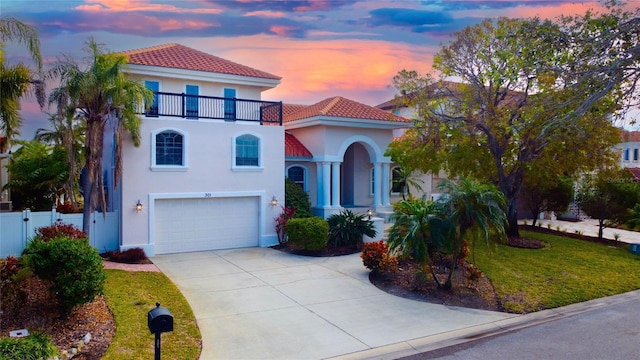 mediterranean / spanish-style home with a lawn, a balcony, and a garage