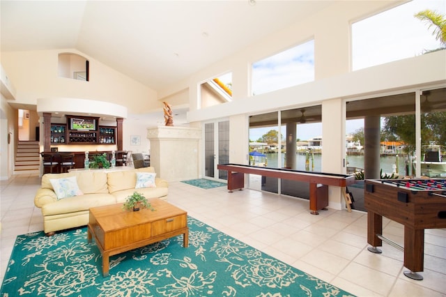 recreation room with tile patterned floors, high vaulted ceiling, and a water view