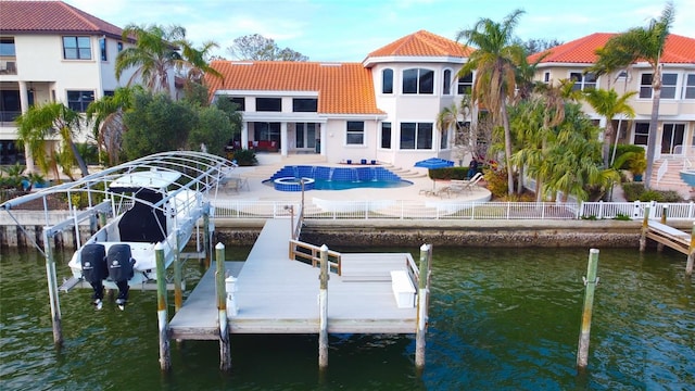 dock with a water view, boat lift, and a patio