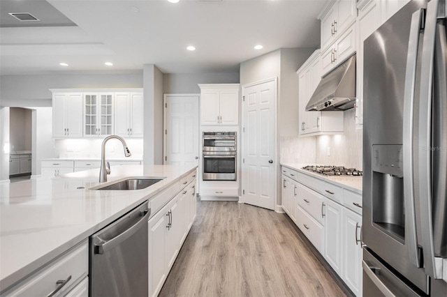 kitchen featuring appliances with stainless steel finishes, white cabinetry, sink, backsplash, and light wood-type flooring