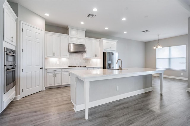 kitchen featuring sink, pendant lighting, a kitchen island with sink, and white cabinetry