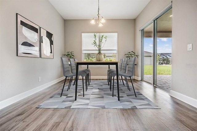 dining space featuring wood-type flooring and an inviting chandelier