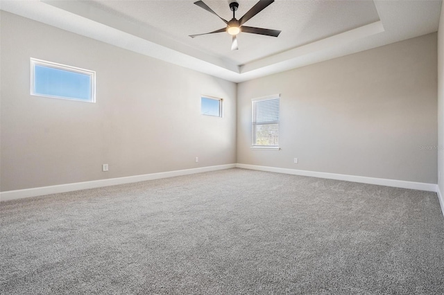 spare room featuring ceiling fan, carpet flooring, and a tray ceiling