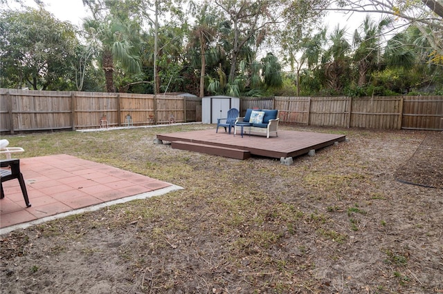 view of yard with a deck, a storage shed, and a patio