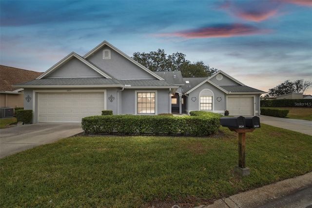 ranch-style home with a garage, central air condition unit, and a lawn