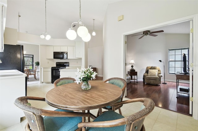 tiled dining area featuring ceiling fan with notable chandelier and high vaulted ceiling