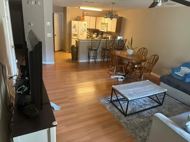 living room with ceiling fan with notable chandelier and light hardwood / wood-style flooring