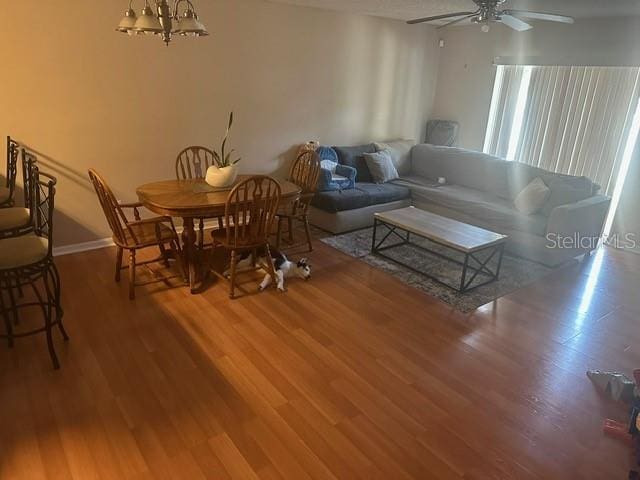 living room featuring ceiling fan with notable chandelier and wood-type flooring