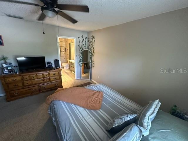 carpeted bedroom featuring ceiling fan, connected bathroom, and a textured ceiling