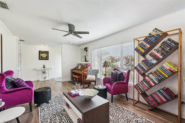 living room featuring a textured ceiling, ceiling fan, and light hardwood / wood-style floors