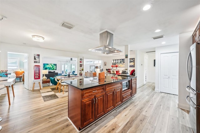 kitchen featuring island exhaust hood, ceiling fan, appliances with stainless steel finishes, light wood-type flooring, and a center island