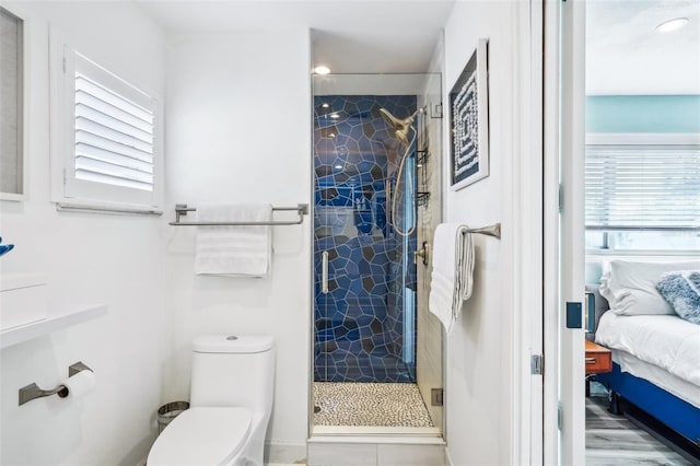 bathroom featuring toilet and a shower with door