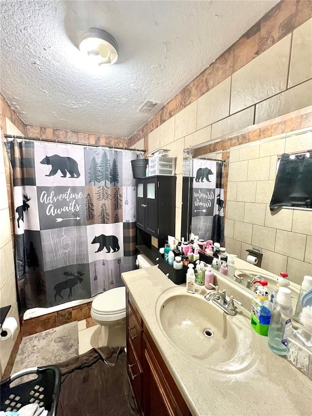 bathroom featuring vanity, toilet, a textured ceiling, and walk in shower