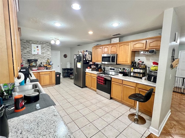 kitchen featuring appliances with stainless steel finishes, sink, light tile patterned floors, and a textured ceiling