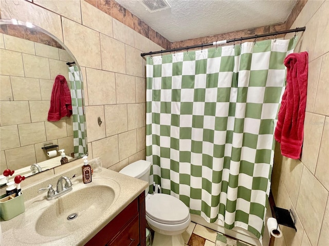 bathroom with tile walls, vanity, walk in shower, toilet, and a textured ceiling