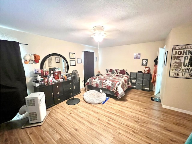 bedroom with a textured ceiling, wood-type flooring, and ceiling fan