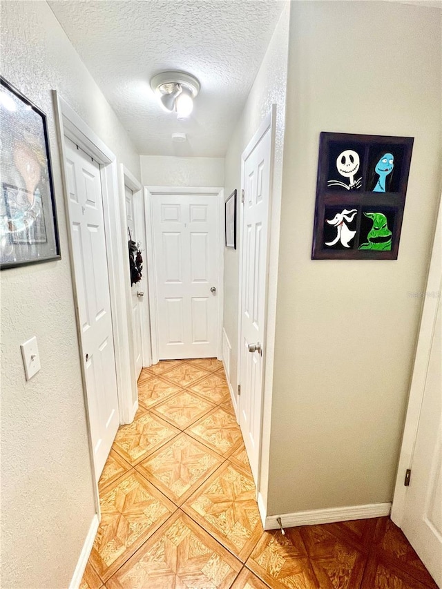 hallway featuring a textured ceiling and baseboards