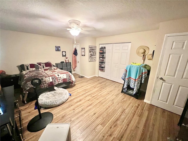 bedroom featuring wood finished floors, a closet, a textured ceiling, baseboards, and ceiling fan