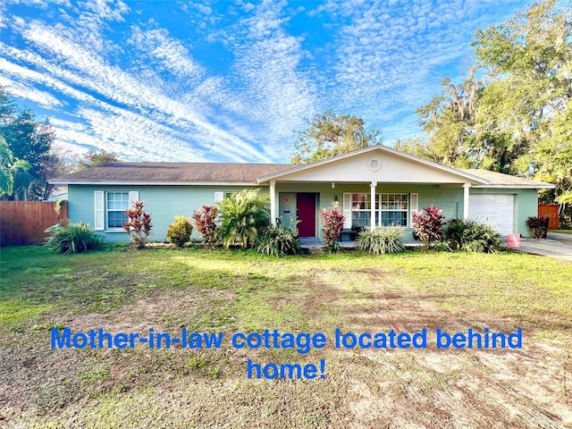 view of front of property with an attached garage, covered porch, fence, and a front yard