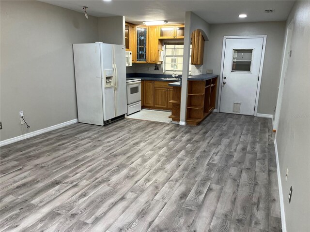 kitchen featuring white appliances, open shelves, light wood finished floors, baseboards, and dark countertops